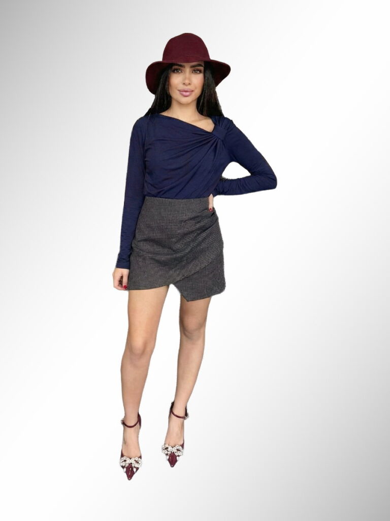 אישה לובשת חולצת טוויסט כחולה עם חצאית מיני אפורה בגזרת מעטפת וכובע בורדו, אופנת נשים, גיליס